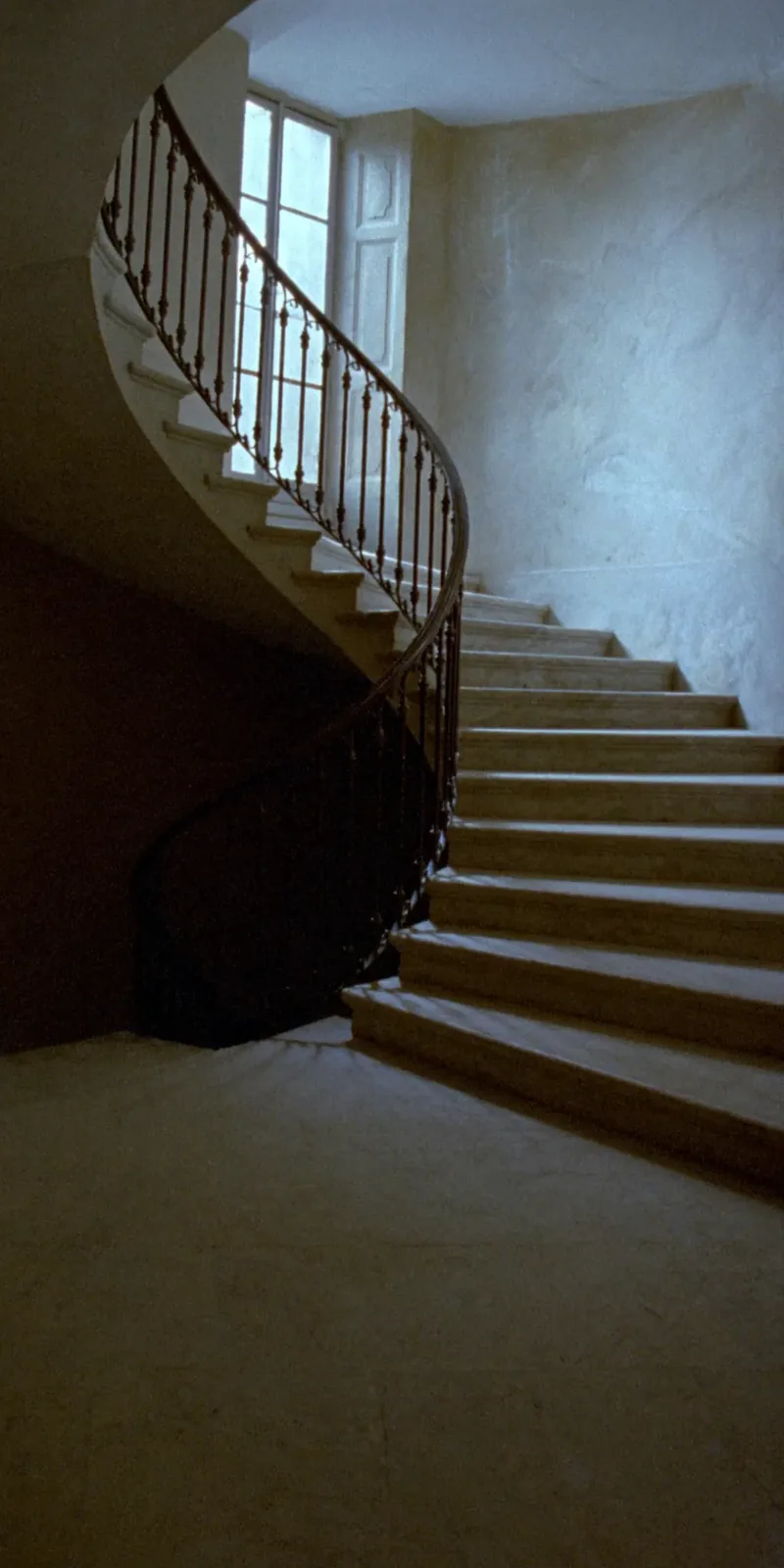L'escalier de pierre, éclairé par une fenêtre haute.